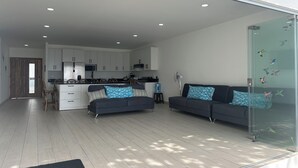 A modern living space with a kitchen, two sofas, and a glass partition with a bird decal. - Luxury Beach house , infinity, pool, breathtaking view, Surf city,Sunset Park. (La Libertad)