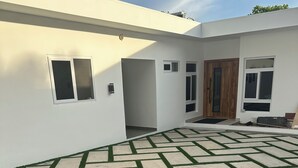 A modern house with a paved patio and a wooden door. - Luxury Beach house , infinity, pool, breathtaking view, Surf city,Sunset Park. (La Libertad)