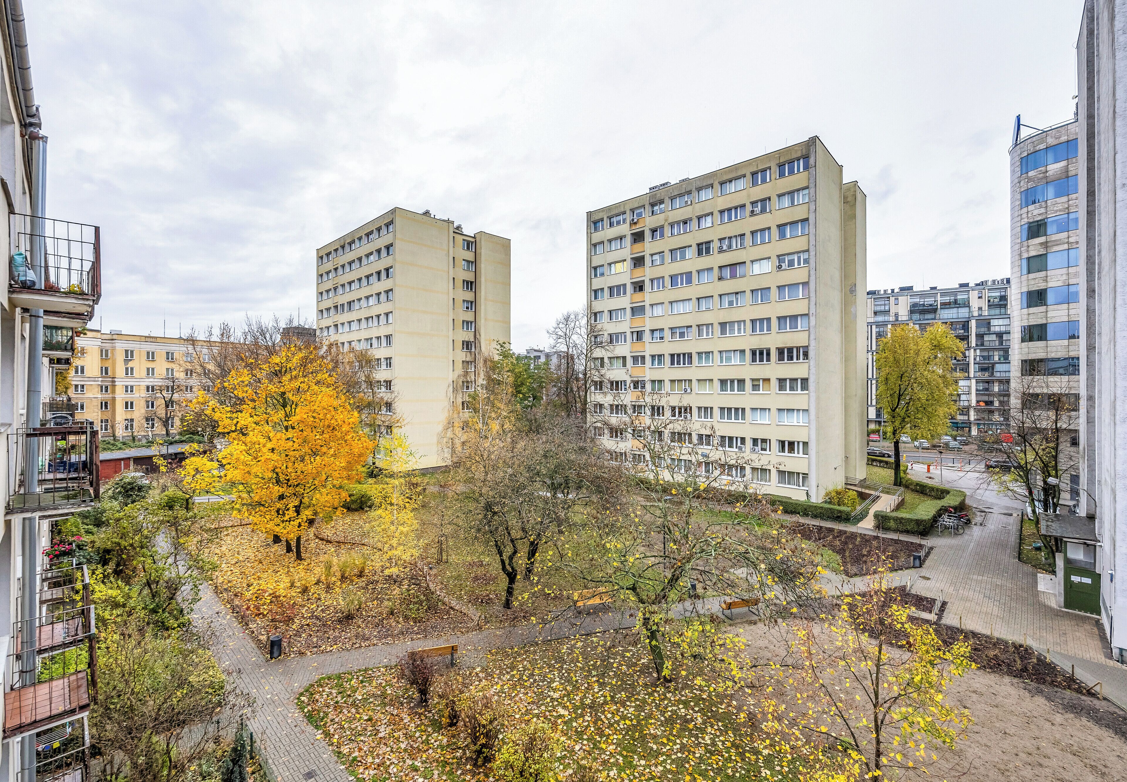 Zona residencial con edificios de apartamentos, un parque con bancos y un sendero pavimentado.