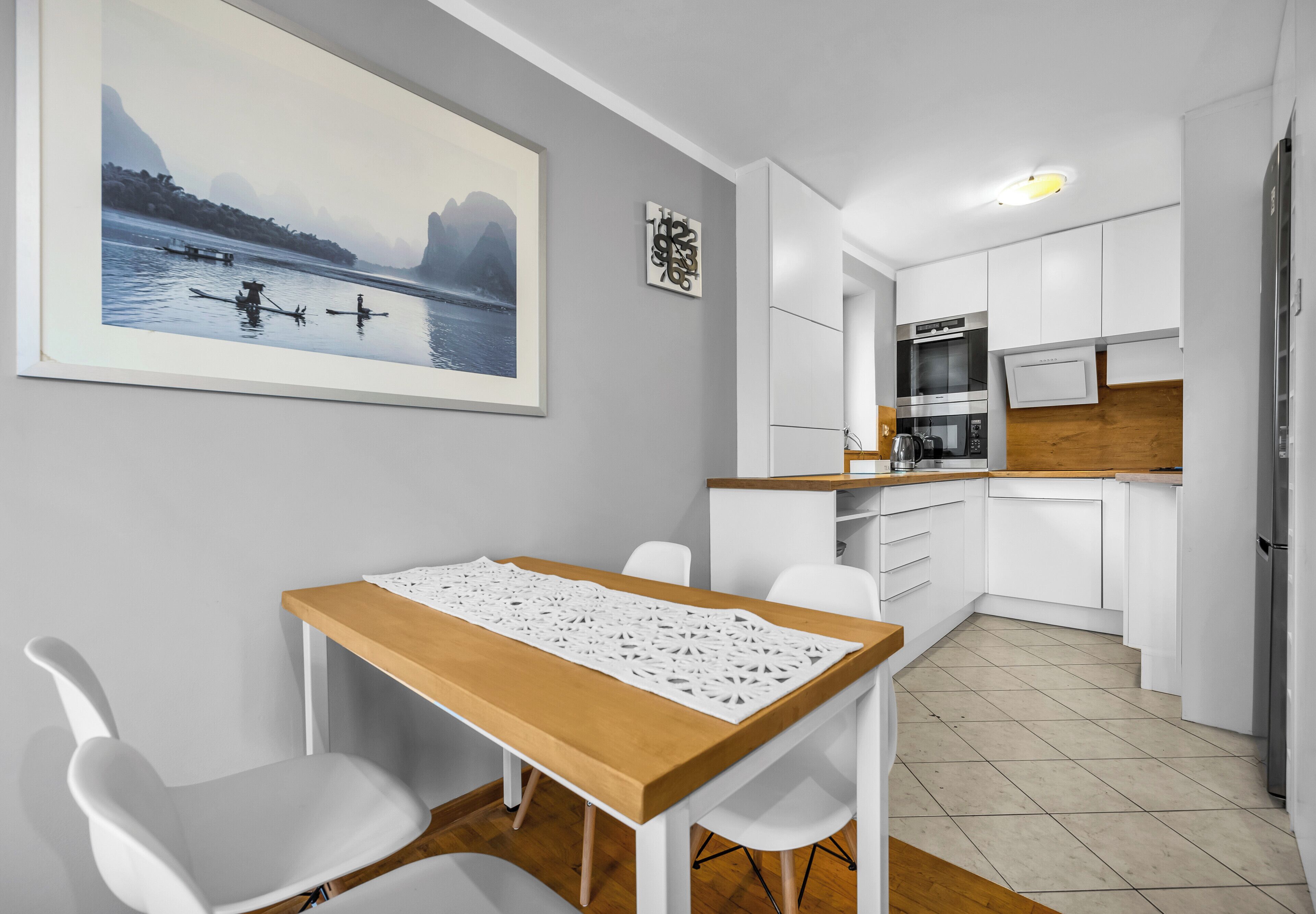 A compact kitchen with white cabinets, a wooden countertop, and a dining area with a table and chairs.