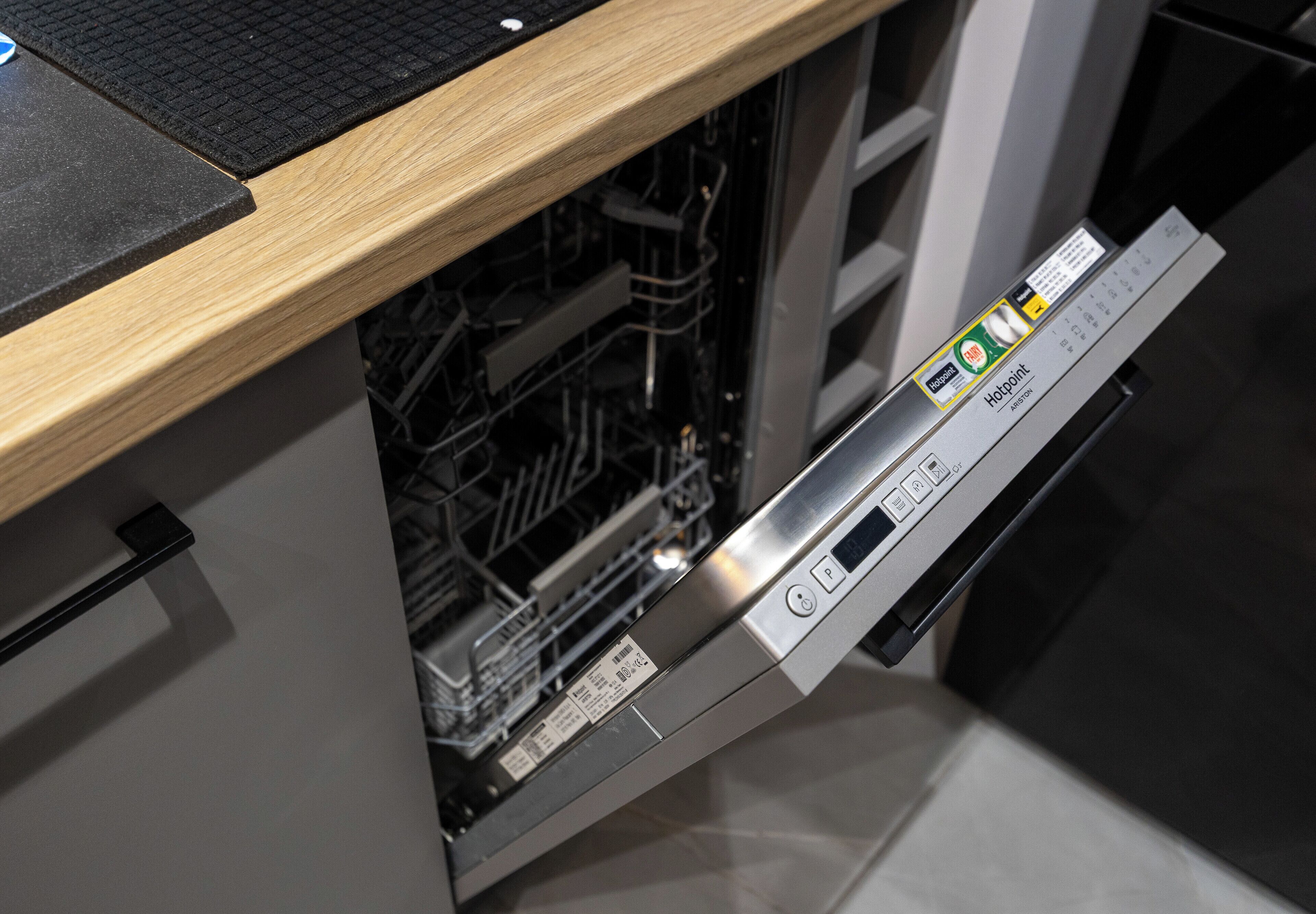 Una cucina moderna con lavastoviglie, piano di lavoro in legno e pannello di controllo digitale.