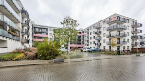 A modern apartment building with balconies, a paved courtyard, and a small tree. - Kłobucka Deluxe Apartment (Warszawa)