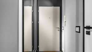 A hallway with a closed door, a wall-mounted phone, and a light switch. - Kłobucka Deluxe Apartment (Warszawa)