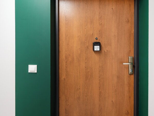Une porte en bois avec un trou de serrure et une serrure, un interphone et un interrupteur à lumière sur le mur.