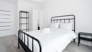 Ein schlicht eingerichtetes Schlafzimmer mit Bett, Kleiderschrank und Regal.