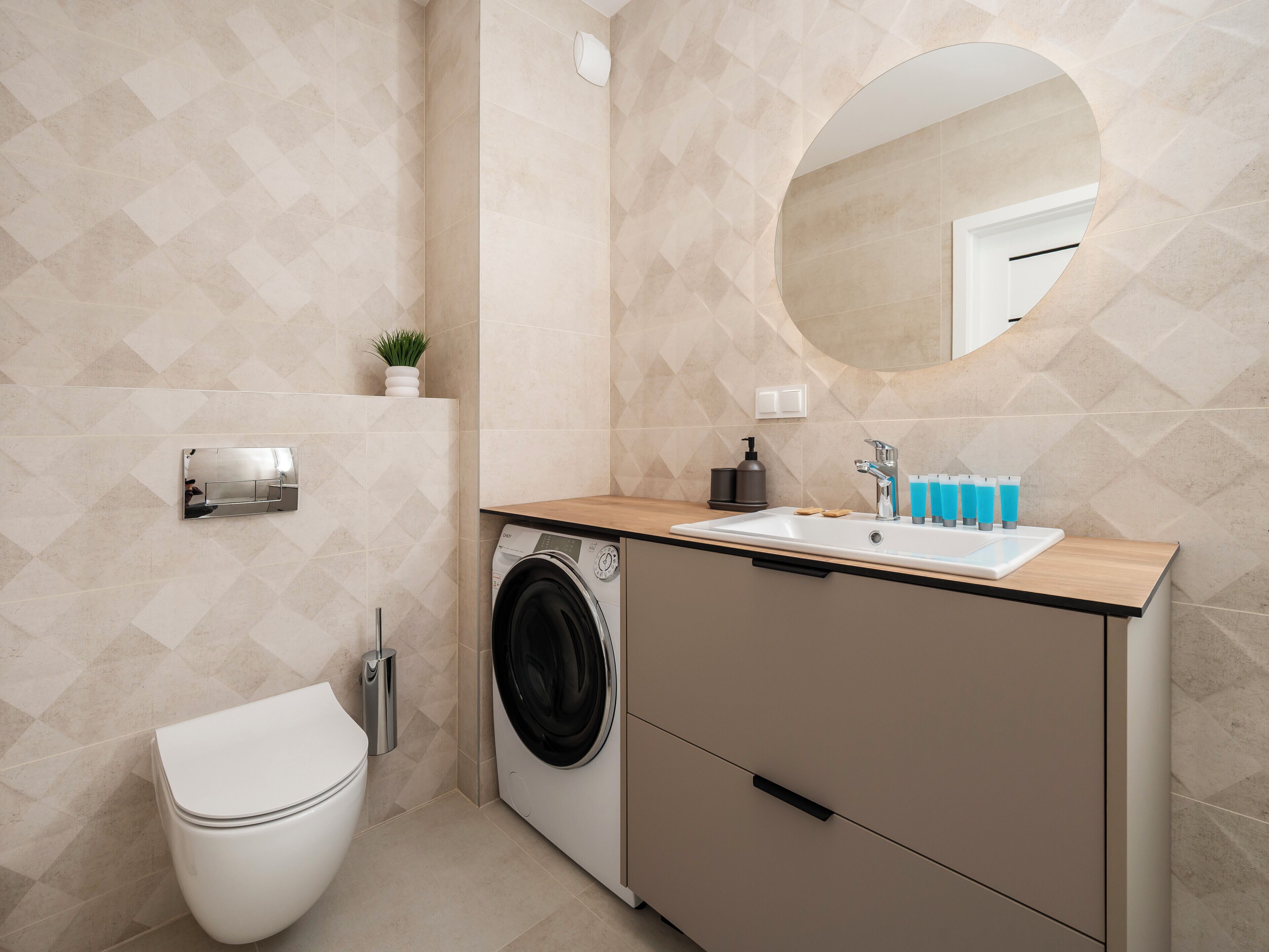 Un baño moderno con lavadora, inodoro, lavabo y espejo.
