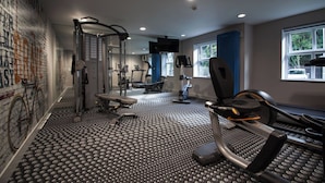 Une salle de sport équipée de tapis de course, d’un banc et d’appareils de musculation.