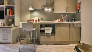 Une petite cuisine équipée comprenant un seul siège, une petite table à manger et un luminaire suspendu.
