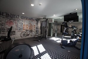 Uma academia com equipamentos de ginástica, uma bicicleta e arte motivacional nas paredes.