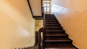 Eine Treppe mit dunklen Holzdielen und einem schwarzen Geländer, die zu einer Tür oben führt.