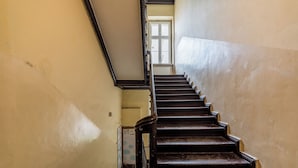 A staircase with dark wooden steps and black railings, leading to a landing with a window. - Heart of Poznań Studio #3 (Poznań)