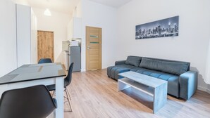 A modern living room with a sofa, a coffee table, a dining table with chairs, and a cityscape painting on the wall. - Heart of Poznań Studio #3 (Poznań)