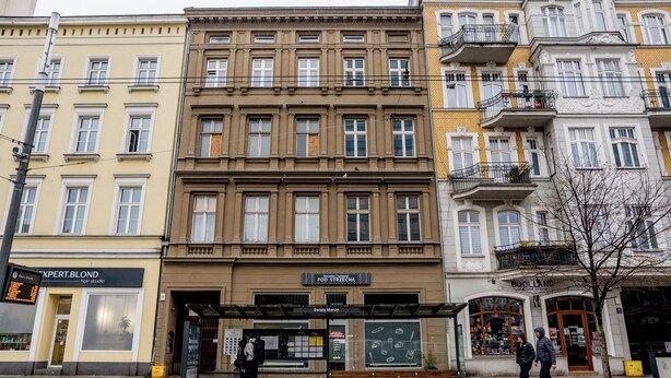Eine Reihe mehrstöckiger Gebäude mit verschiedenen Geschäften, darunter ein Friseursalon und eine Buchhandlung.