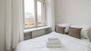 Ein Schlafzimmer mit einem großen Fenster, weißer Bettwäsche und einer Heizung.