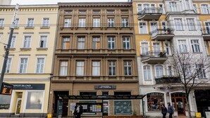 En rad av fler våningar höga byggnader med olika butikslokaler, bland annat en frisörsalong och en bokhandel.