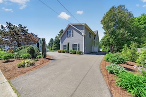 A two-story house with a driveway leading to the front door, surrounded by well-maintained landscaping and trees. - Downtown Guilford Studio - Walk to Green, Beach & Train (Guilford)