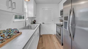 Een moderne keuken met witte kasten, een roestvrijstalen koelkast en een houten aanrecht.