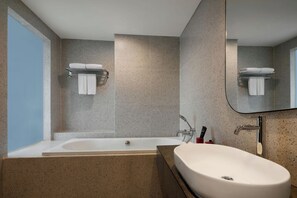 Een moderne badkamer met een vrijstaand bad, een wastafel en een grote spiegel.