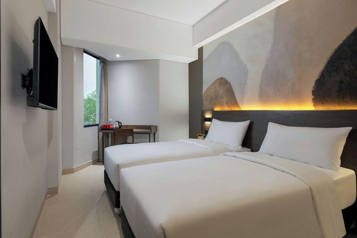 Een moderne hotelkamer met twee bedden, een bureau en een televisie.