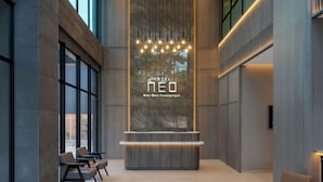Un hall d’hôtel moderne avec un comptoir d’accueil, un espace salon et de grandes fenêtres.