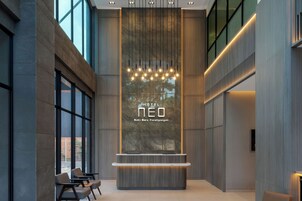 Un moderno vestíbulo de hotel con recepción, zona de estar y amplios ventanales.