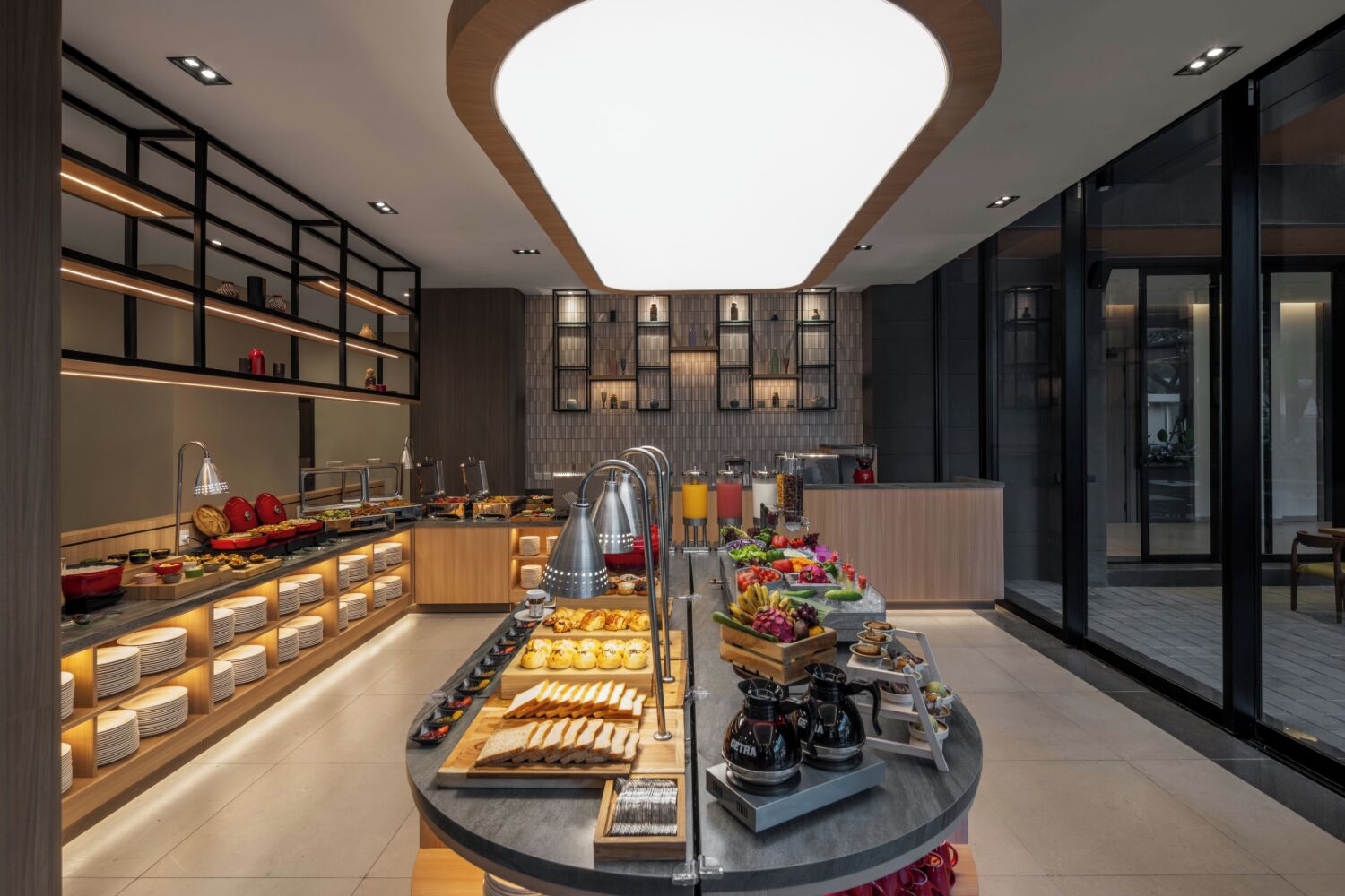 A modern breakfast buffet with a variety of food items and beverages, a coffee station, and a seating area with a view.