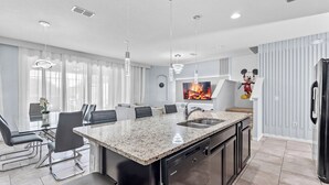A modern kitchen with a granite countertop, stainless steel appliances, and a dining area with black chairs and a glass table. - NEW! Solterra Townhome, Private Pool, 4 Bedroom, 3.5 Bathroom, 15 min to Disney (Davenport)