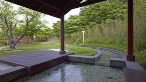 A tranquil garden with a wooden deck, a curved water feature, and lush greenery. - Kinock Pet Hotel (Gyeongju)