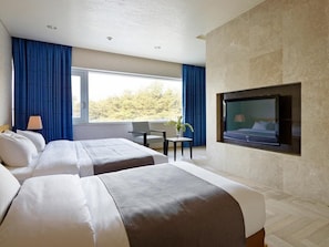 A hotel room with two beds, a TV mounted on the wall, a small table with a lamp, and a window with curtains. - Kinock Pet Hotel (Gyeongju)