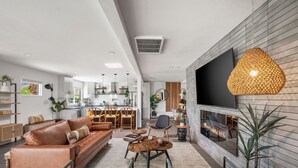 Un salon moderne avec un canapé en cuir, une table basse et un téléviseur fixé au mur, qui est de couleur blanche.