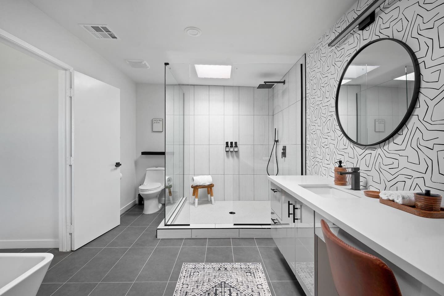 A modern bathroom with a shower, toilet, and sink.