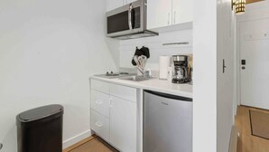 Una cuina compacta amb armaris blancs, microones, cafetera i rentaplats.