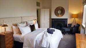 A hotel room with a bed, a chair, a dresser, a fireplace, and a lamp. - Penthouse Ozone in Queenscliff (Queenscliffe)