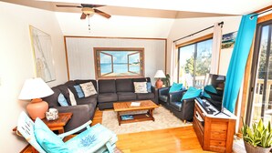 A living room with a sofa, coffee table, and a view of the sea through a window. - Oceanside, Close to beach, Hot Tub, Dogs Welcome-CI2, Brass Ring (Duck)