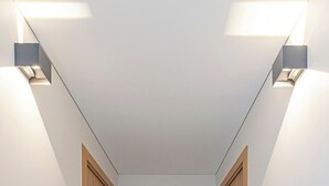 A narrow hallway with wooden doors, a tiled floor, and two wall-mounted lights. - Vytauto 43 Residence – Lietūkis by Domvia (Kaunas)