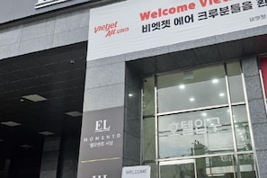 L’entrée d’un hôtel, avec une pancarte « Bienvenue » et le nom « EL MOMENTO » inscrit sur la façade.