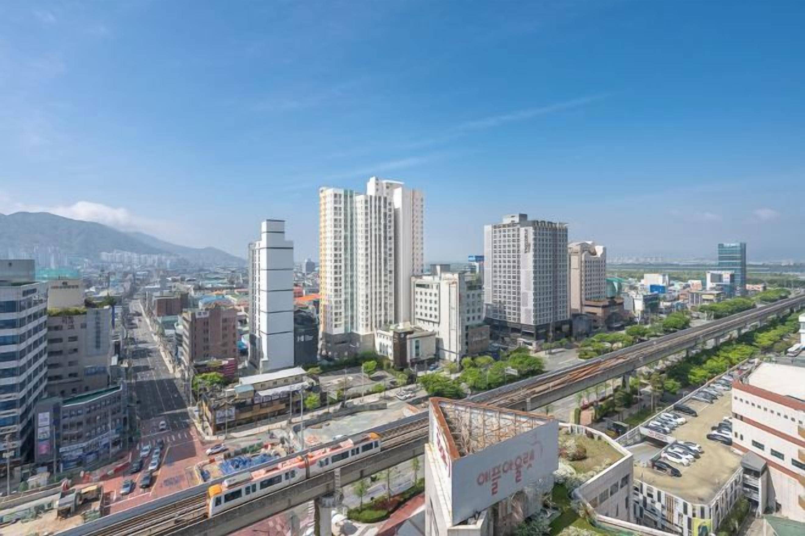 Un paisaje urbano con rascacielos, una autopista y una vía de tren.