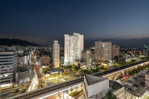 A cityscape at night with high-rise buildings, a highway, and a bridge. - El Momento Sasang (Busan)