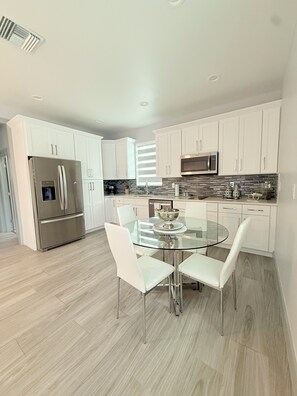 A modern kitchen with white cabinets, stainless steel appliances, and a glass dining table. - Charming 1-bedroom building in fabulous Tampa with AC (Tampa)
