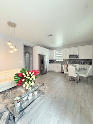 A modern kitchen with white cabinets, stainless steel appliances, and a dining area with a glass table and chairs. - Charming 1-bedroom building in fabulous Tampa with AC (Tampa)