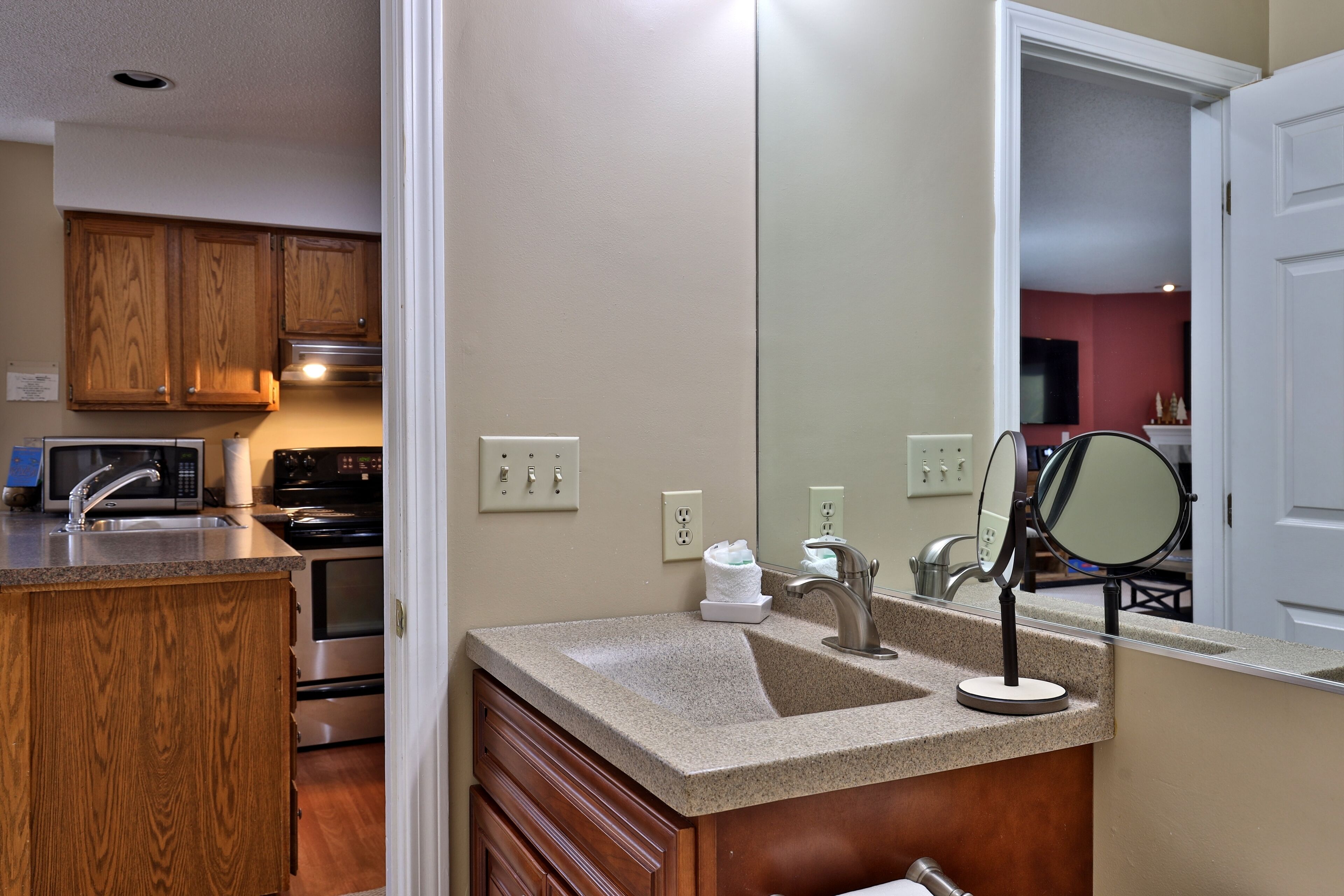 A kitchen with wooden cabinets, a granite countertop, a sink, a stove, and a microwave.
