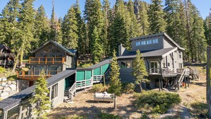 A cabin complex with multiple buildings, including a main house with a balcony and a smaller structure with a covered deck. - Panoramic Peaks at Alpine by Tahoe Getaways - Pet-Friendly, A/C, Hot Tub, Shuttle & Stunning Views (Alpine Meadows)