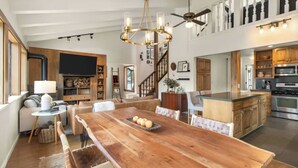 A spacious living area with a large wooden dining table, a chandelier, and a ceiling fan. - Panoramic Peaks at Alpine by Tahoe Getaways - Pet-Friendly, A/C, Hot Tub, Shuttle & Stunning Views (Alpine Meadows)
