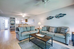 A living room with two grey sofas, a wooden coffee table, and a ceiling fan. - Sun Stack at Runaway Bay 251 by SeaBreeze Vacation (Bradenton Beach)