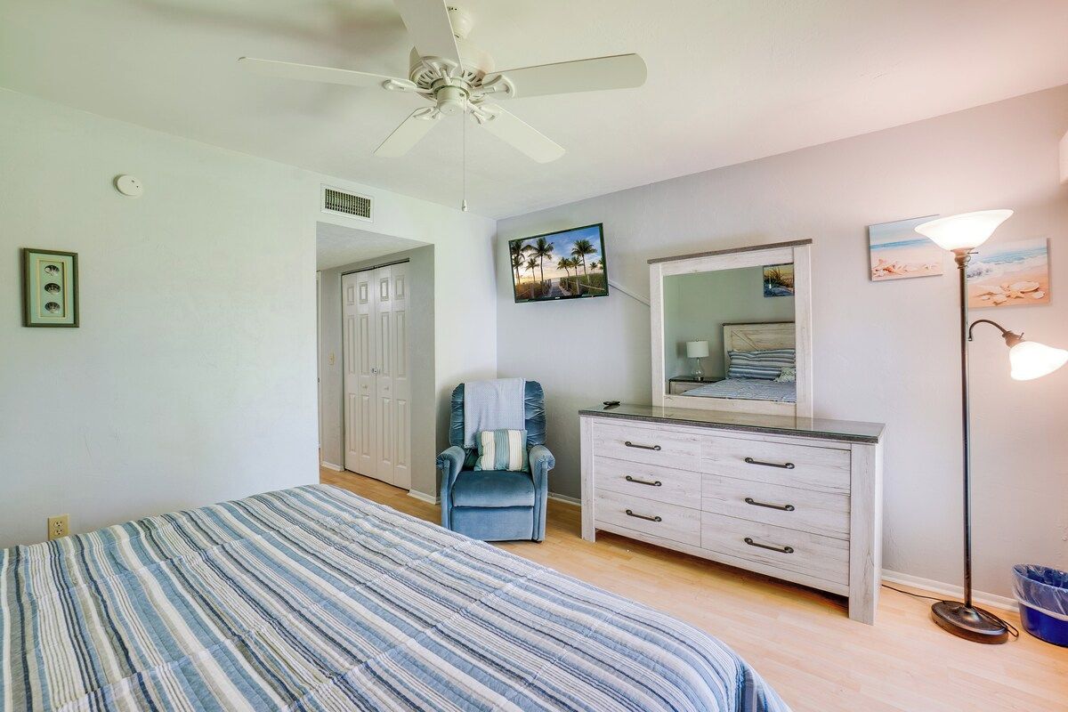 Un dormitorio con cama, una silla, cómoda, ventilador de techo y decoración en la pared.