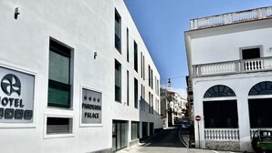 A narrow street with white buildings, one labeled "HOTEL" and another "PANORAMA PALACE". - Casa Nicanto (Meta)