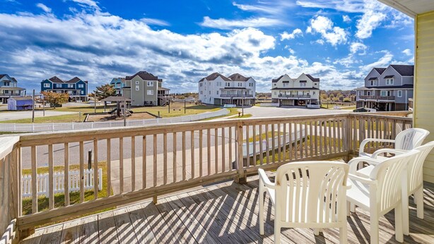 A residential area with multiple houses, a playground, and a wooden deck with chairs.