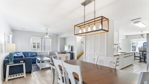 A modern kitchen with a central island, white cabinetry, and a hanging light fixture.