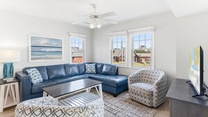 A modern living room with a sectional sofa, a patterned armchair, a coffee table, and a TV.