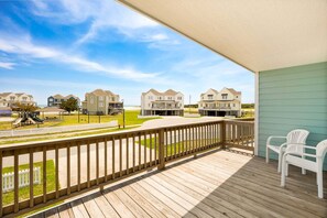 A wooden deck with a view of beach houses and a playground. - Pollock: Bright Buxton Townhouse w/ Ocean Views (Buxton)